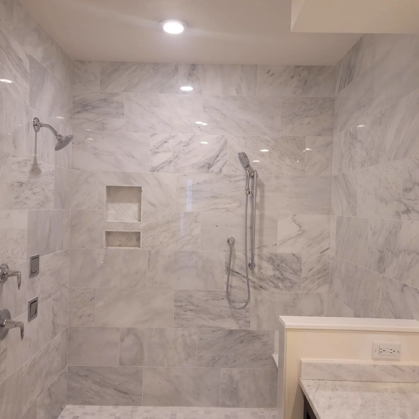 Curbless marble walk-in shower with corner niche shelving