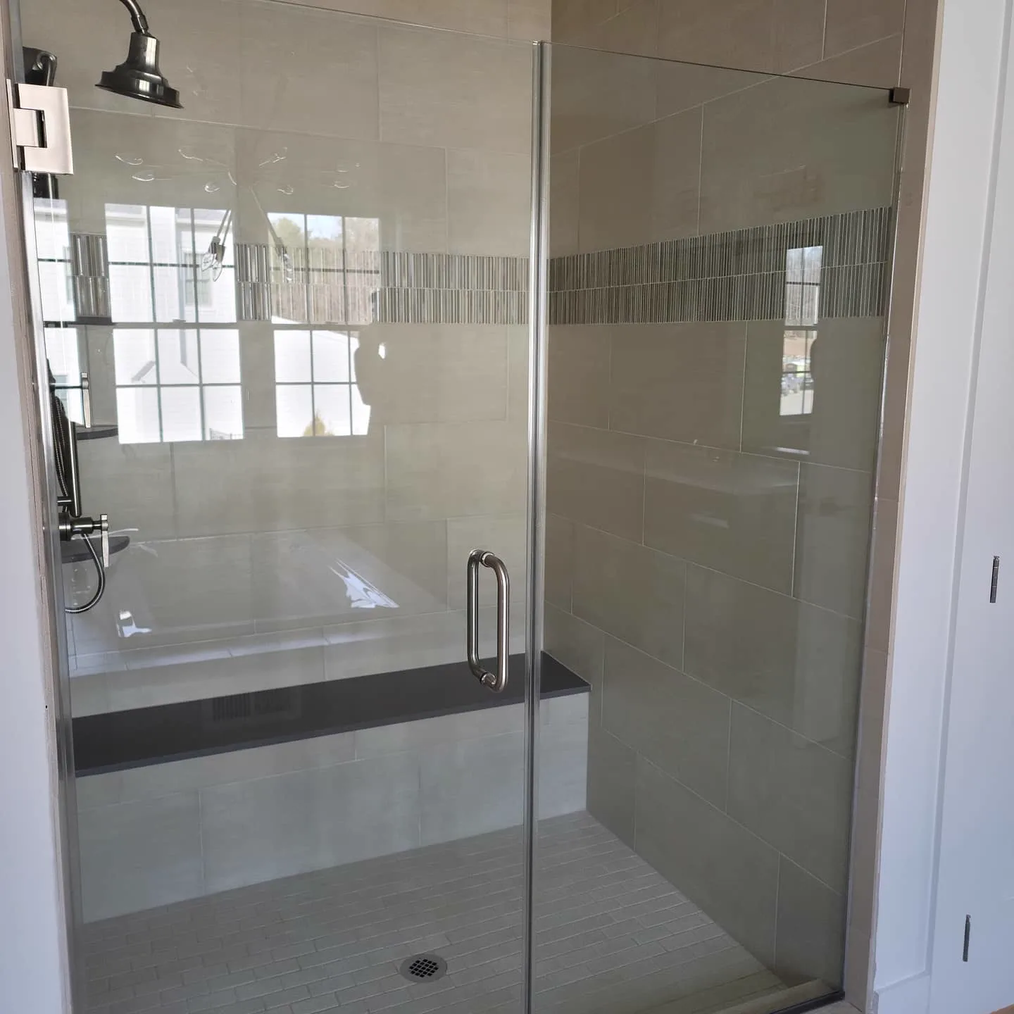 Glass-door shower with tiled walls and bench
