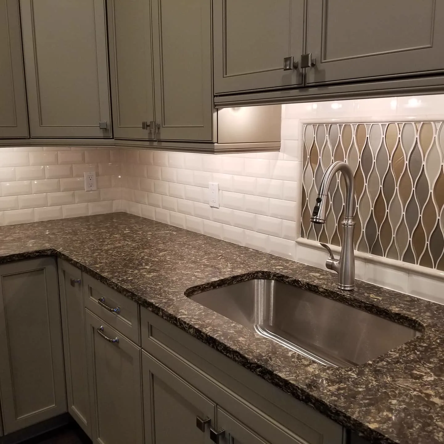 Kitchen with cream cabinets, dark granite, and subway backsplash