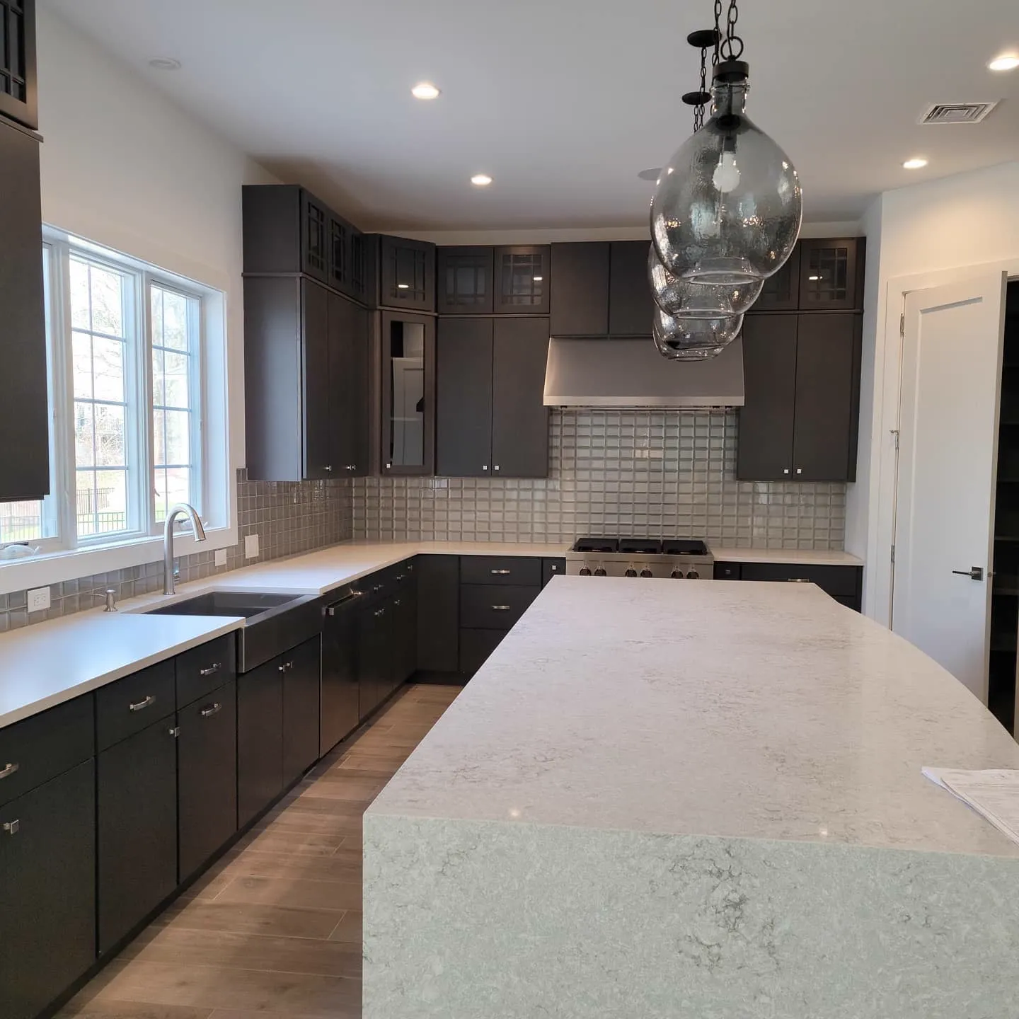 Kitchen with dark cabinetry, island, and pendant lighting