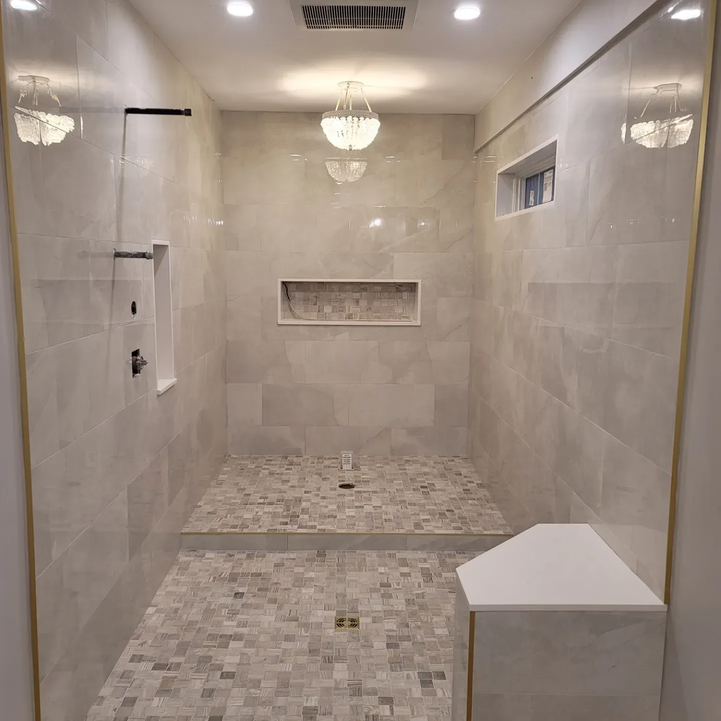 Walk-in shower with gold trim and mosaic floor