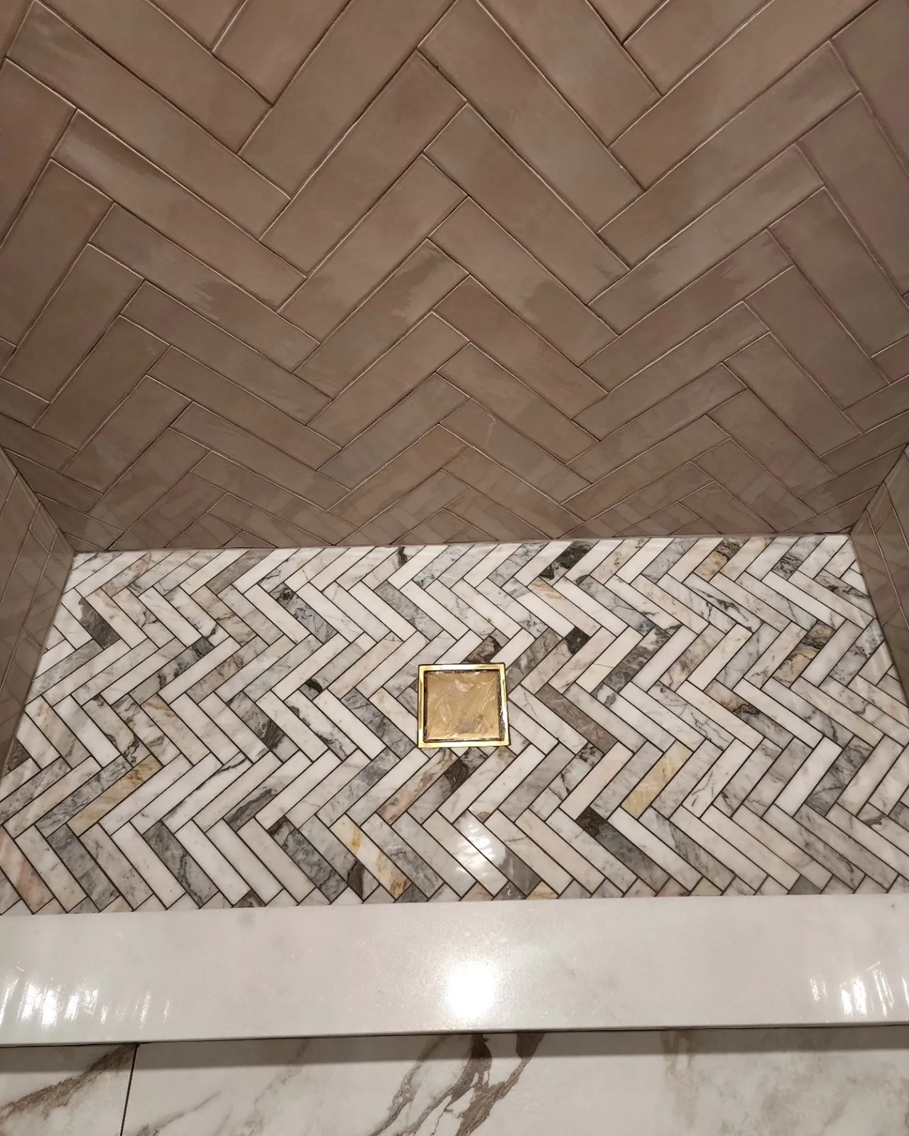 Herringbone tile shower wall and floor with linear drain